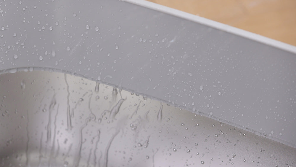 Close-up of water droplets on a gray cat litter box showing its leak proof seal.