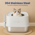 Load image into Gallery viewer, A fluffy cat sits in a modern stainless steel top entry cat litter box with a white, ribbed top and a scooper on the side, against a beige wall.