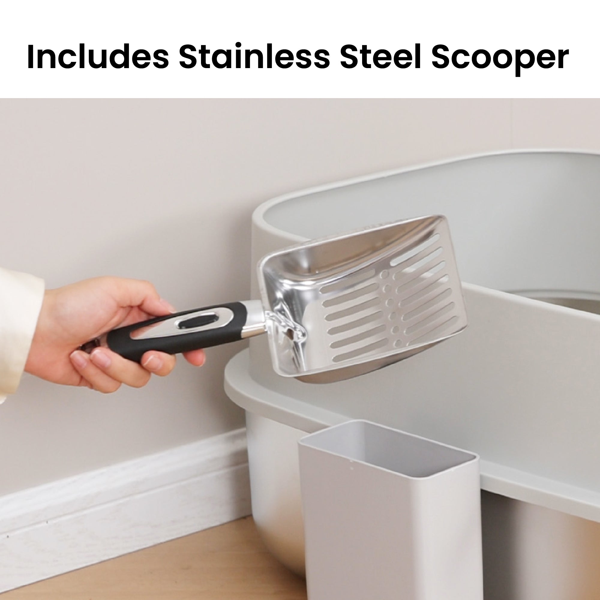 Hand holding a stainless steel litter scooper next to PawsPik cat litter box.