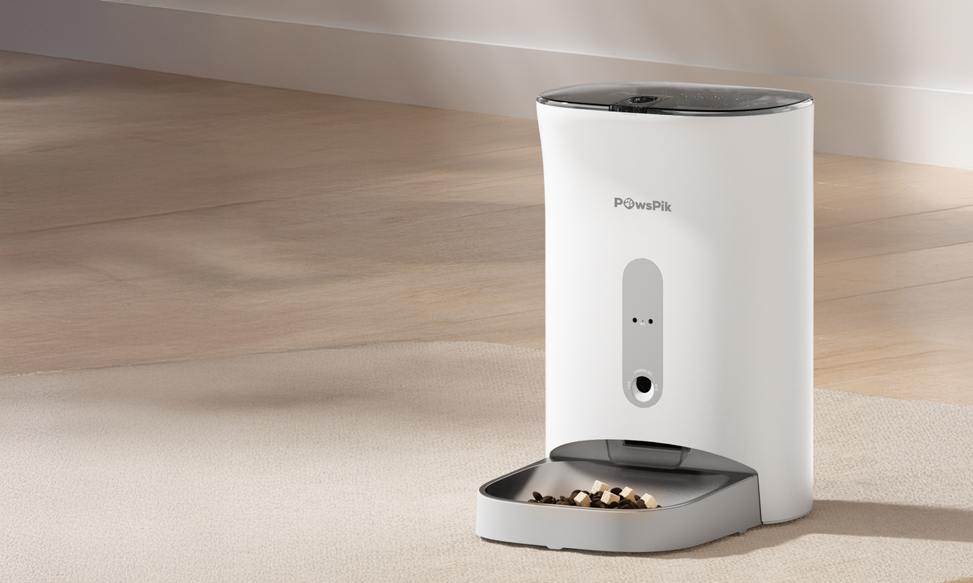 A sleek white automatic cat feeder dispenses kibble into a gray dish on a light carpeted floor, angled in soft natural light, creating a calm atmosphere.