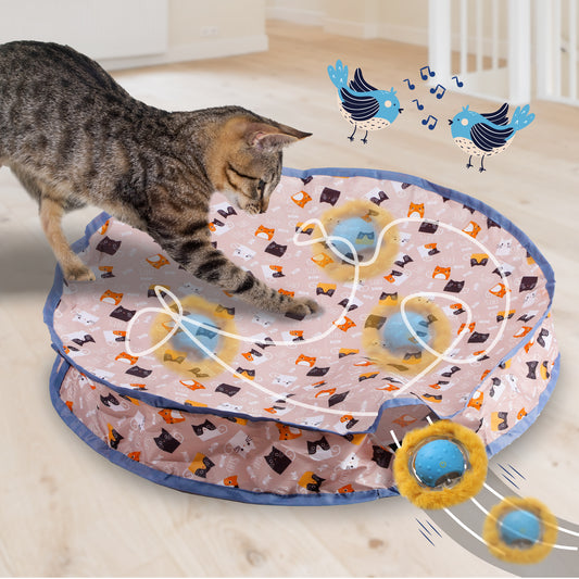 A playful tabby cat interacts with a colorful, patterned cat toy featuring moving balls, with whimsical bird illustrations above.