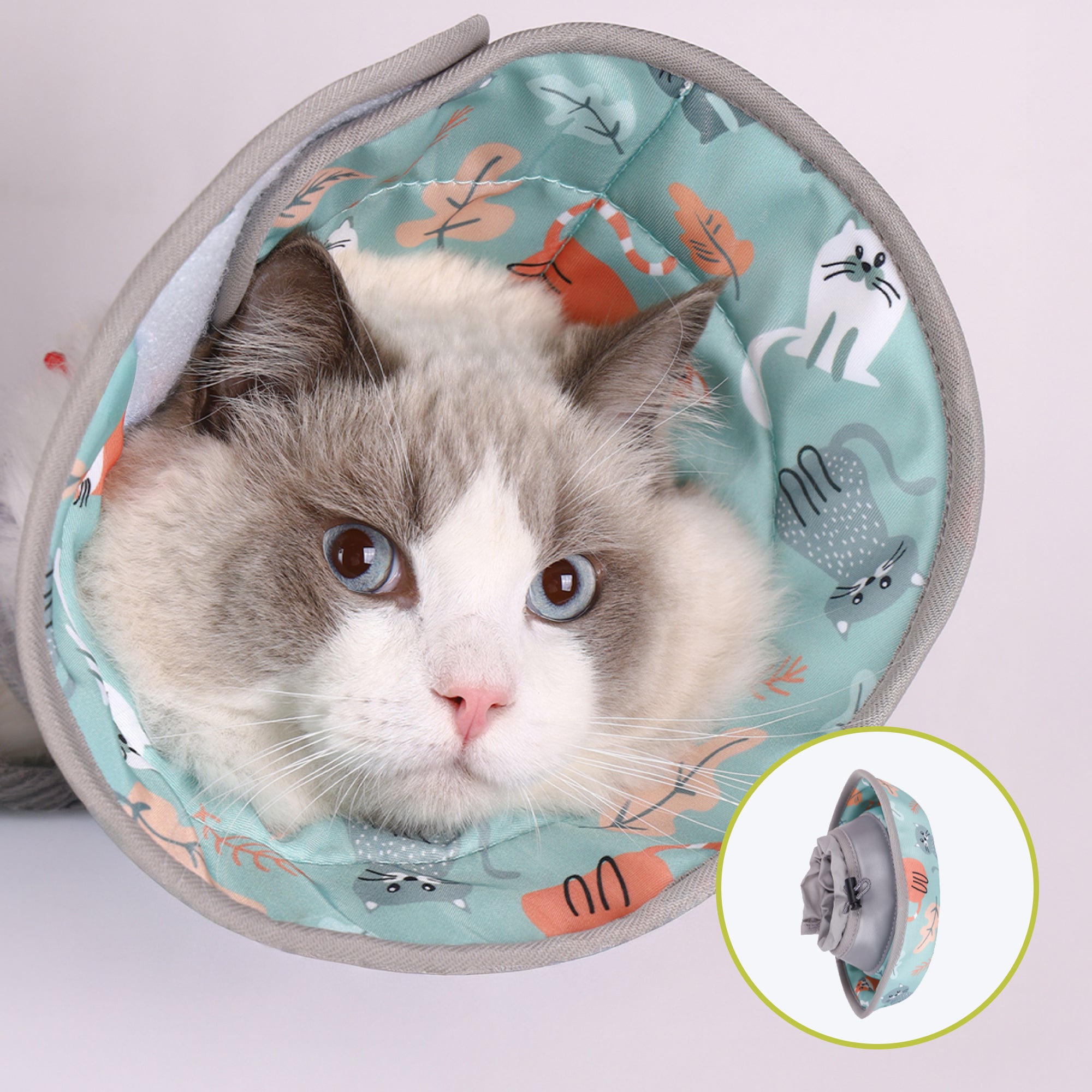 A close-up of a cat nestled inside a cozy, patterned soft cone for cats featuring playful illustrations of animals and foliage.
