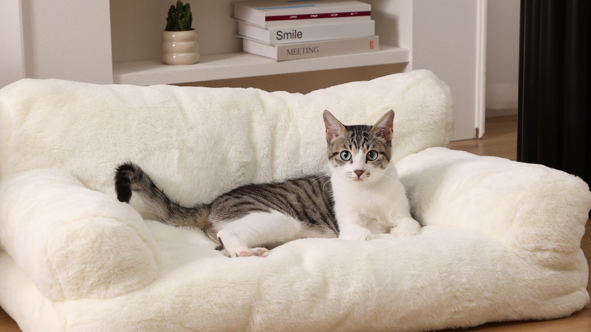 Cat lying on a fluffy white pet bed in a cozy room.