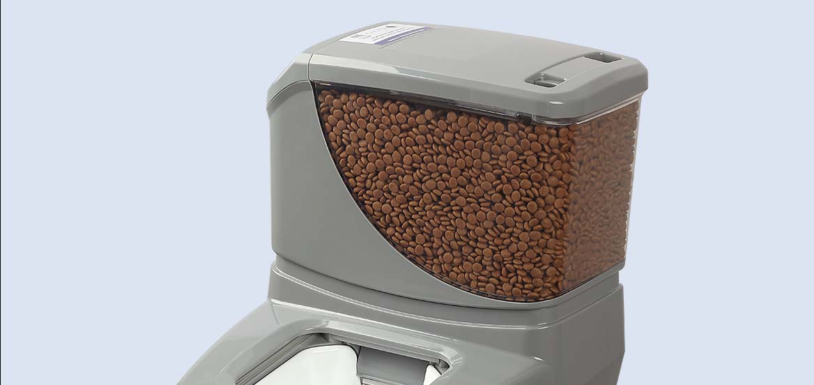 Automatic pet feeder filled with dry food against a grey background.